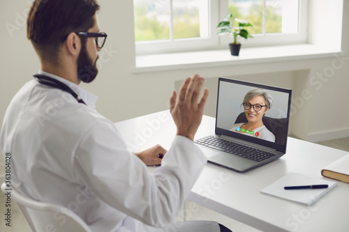 Doctor online. Senior woman patient tells symptoms of illness to doctor using laptop video chat consultation virtual clinic.