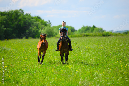 One Caucasian horsewoman is riding through the field.
