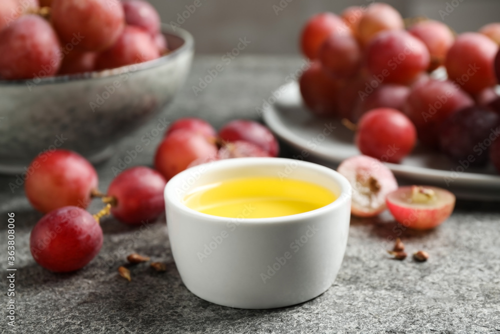 Bowl of natural grape seed oil on grey table. Organic cosmetic Bowl of natural grape seed oil on grey table. Organic cosmetic