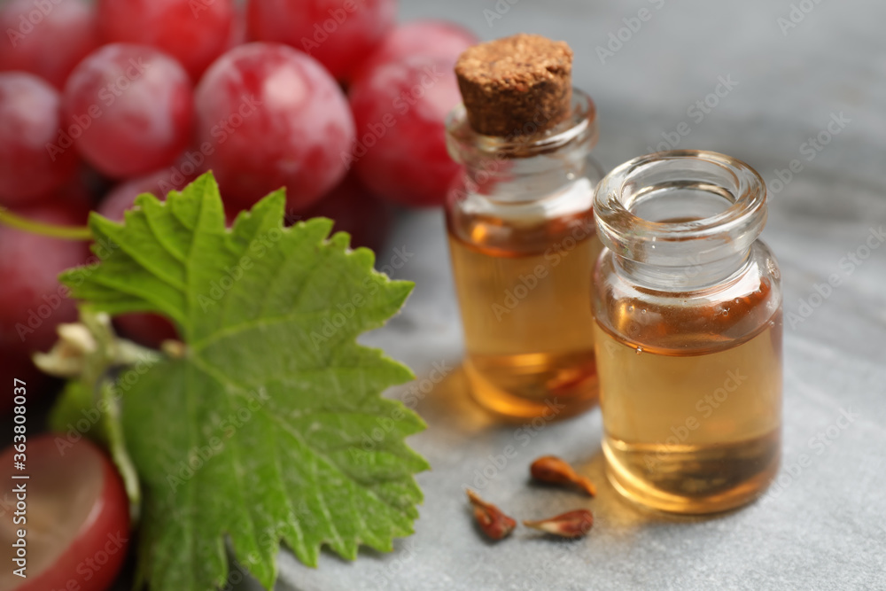 Bottles of natural grape seed oil on grey table. Organic cosmetic Bottles of natural grape seed oil on grey table. Organic cosmetic