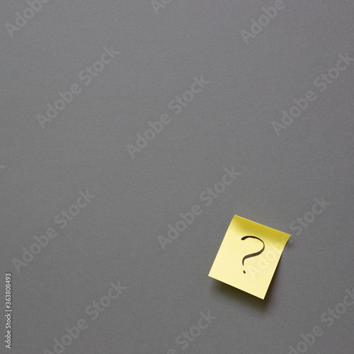 Question mark on sticky memo paper on gray background. Solution concept