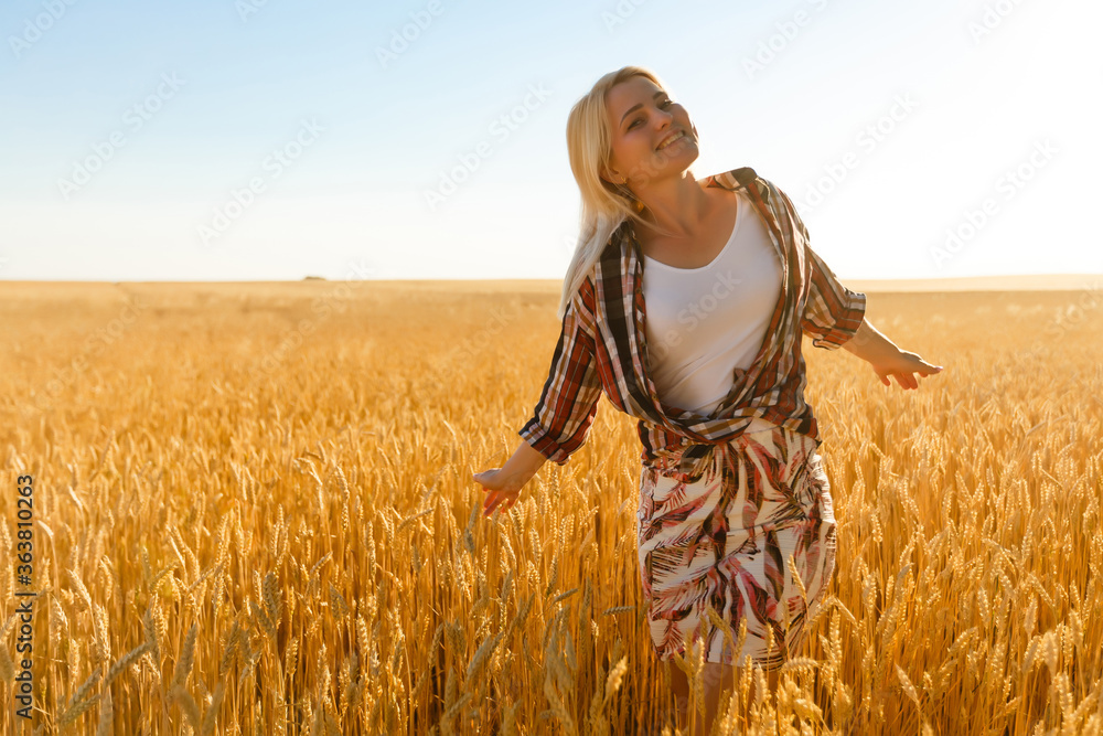 Naklejka premium A girl in the midst of wheat spikelets. Caucasian woman posing with spikelets outside.