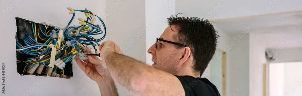 Obraz premium Electrician working on the electrical installation of a house