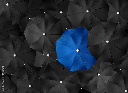Konstfotografi Concept image with lots of black umbrellas and a blue umbrella that stands out,
