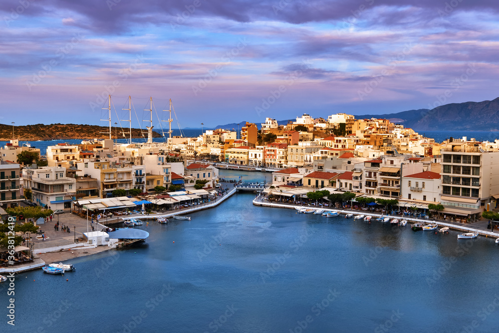 Colorful view of Voulismeni lake and Agios Nikolaos town on Crete island, Greece at sunset with beautiful clouds on blue sky Colorful view of Voulismeni lake and Agios Nikolaos town on Crete island, Greece at sunset with beautiful clouds on blue sky