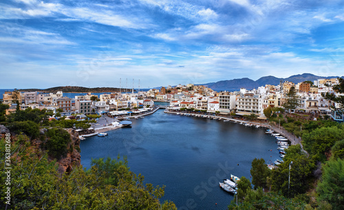 Colorful view of Voulismeni lake and Agios Nikolaos town on Crete island, Greece in evening with beautiful clouds on blue sky. © NPershaj