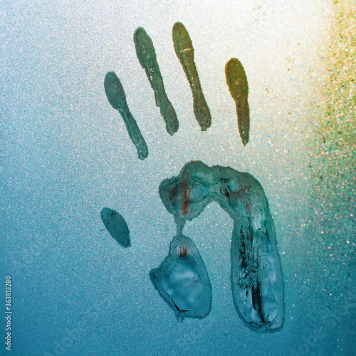 imprint rugas and feet on glass covered with hoarfrost in the cold winter season photo