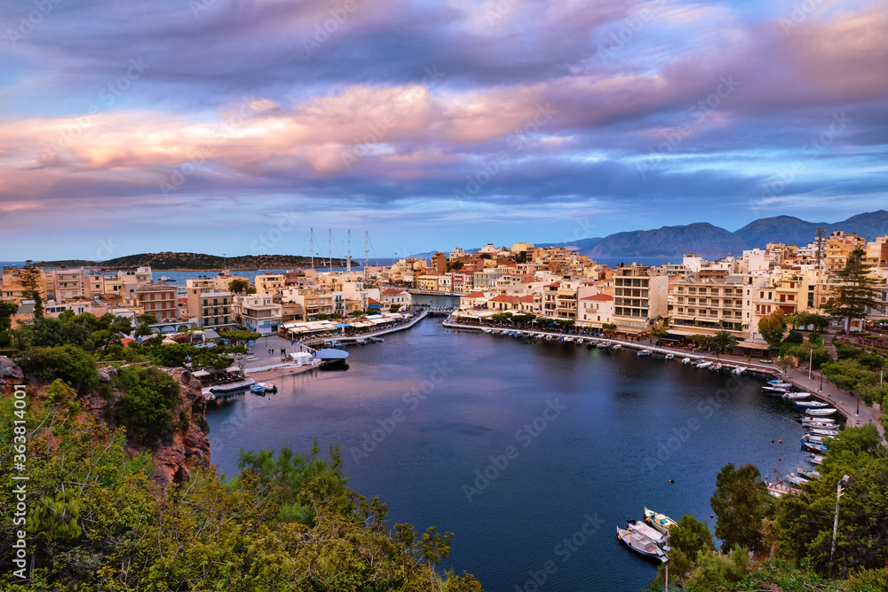Colorful view of Voulismeni lake and Agios Nikolaos town on Crete island, Greece at sunset with beautiful clouds on blue sky