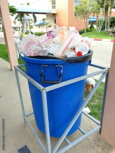 garbage bin full with plastic glasses and bags in the park.