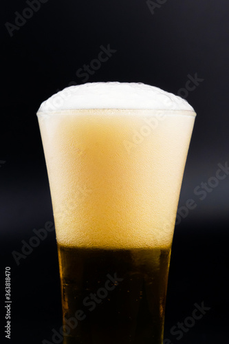 Beer glass with beer bubbles on a black background.