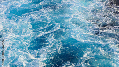 seething water. texture of blue foamy sea water. clear ocean water background. sun reflection