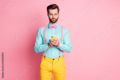 Photo of serious focused macho man use smartphone read social network news follow post comment wear yellow pants trousers isolated over pastel color background