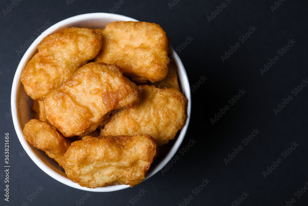 Bucket with delicious chicken nuggets on black background, top view. Space for text Bucket with delicious chicken nuggets on black background, top view. Space for text