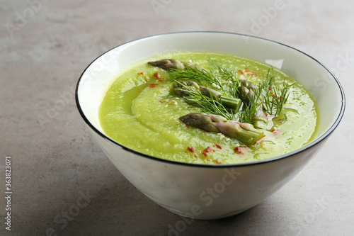 Delicious asparagus soup in bowl on grey table