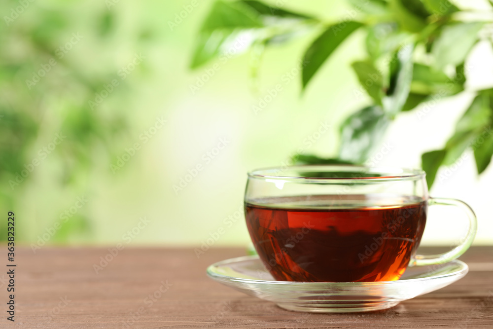 Cup of black tea on wooden table against blurred background. Space for text Cup of black tea on wooden table against blurred background. Space for text
