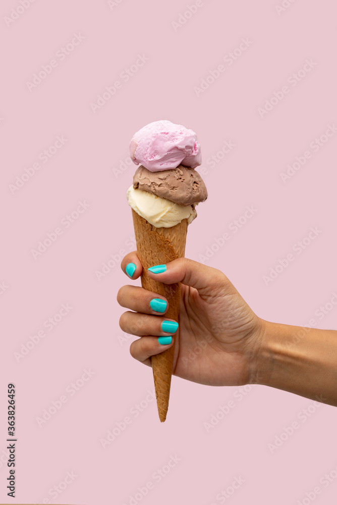 Woman's hand holding an ice cream over a pink background Woman's hand holding an ice cream over a pink background
