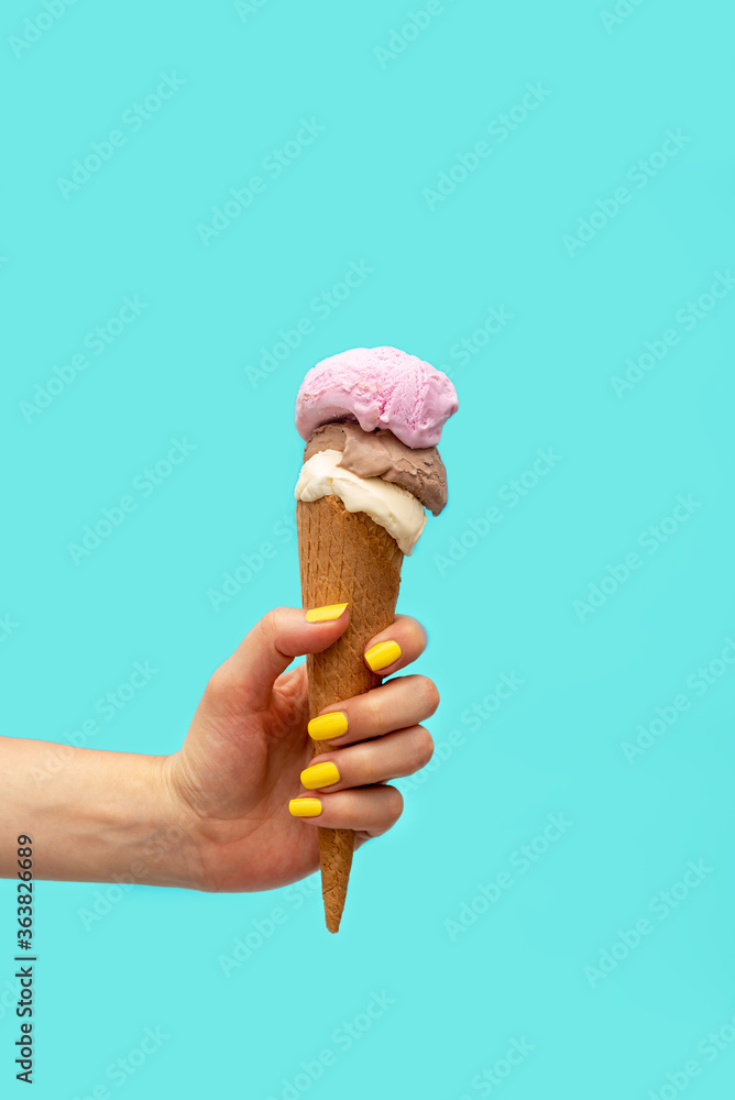 Woman's hand holding an ice cream over a light blue background Woman's hand holding an ice cream over a light blue background