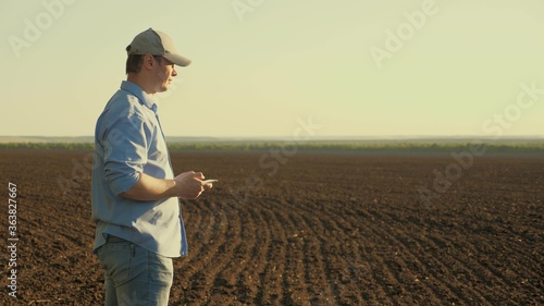 farmer man with tablet in the field. male agronomist checks the quality of sowing grain. businessman checks his field. farmer checks the quality of the soil before sowing.