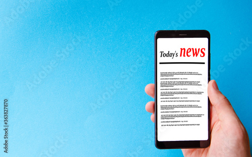 A male hand holds a smartphone, points a finger, types. Communication on a smartphone, correspondence. Place for text. Smartphone in hand on a blue  background.