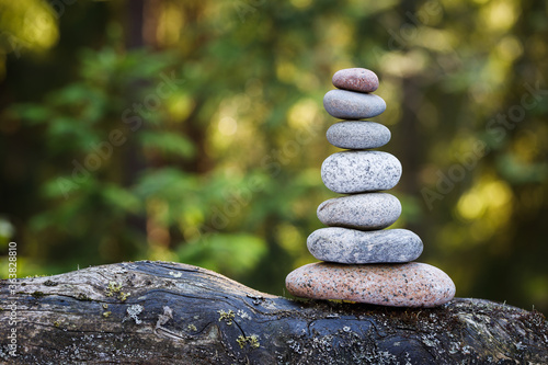 Pyramid stones balance on a tree trunk in the forest. Pyramid in focus  forest background is blurred.