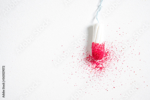 White women's tampon on white background and red glitter pigment. Concept photography for women's or feminist blog 