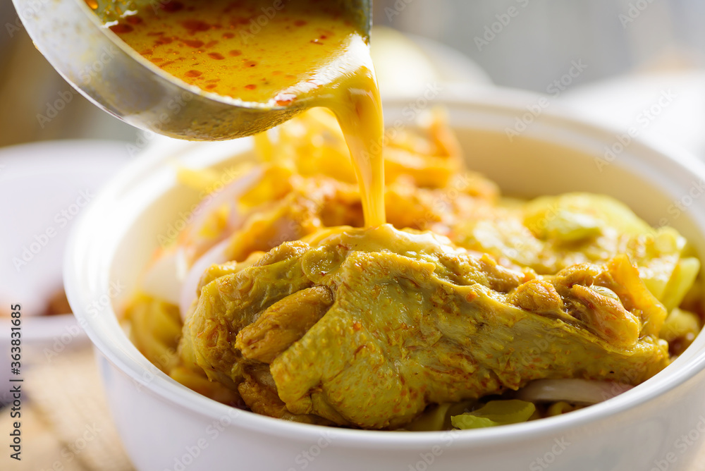 Northern Thai food (Khao Soi), Spicy curry noodles soup with chicken cooking in a bowl Northern Thai food (Khao Soi), Spicy curry noodles soup with chicken cooking in a bowl
