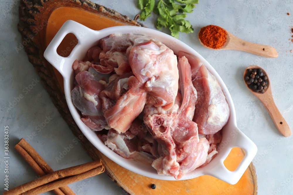 Fresh raw goat meat or mutton or lamb pieces. Preparation for Indian mutton curry. Spice at the background such as cinnamon sticks, red chili powder, black pepper & coriander. Copy space. Fresh raw goat meat or mutton or lamb pieces. Preparation for Indian mutton curry. Spice at the background such as cinnamon sticks, red chili powder, black pepper & coriander. Copy space.