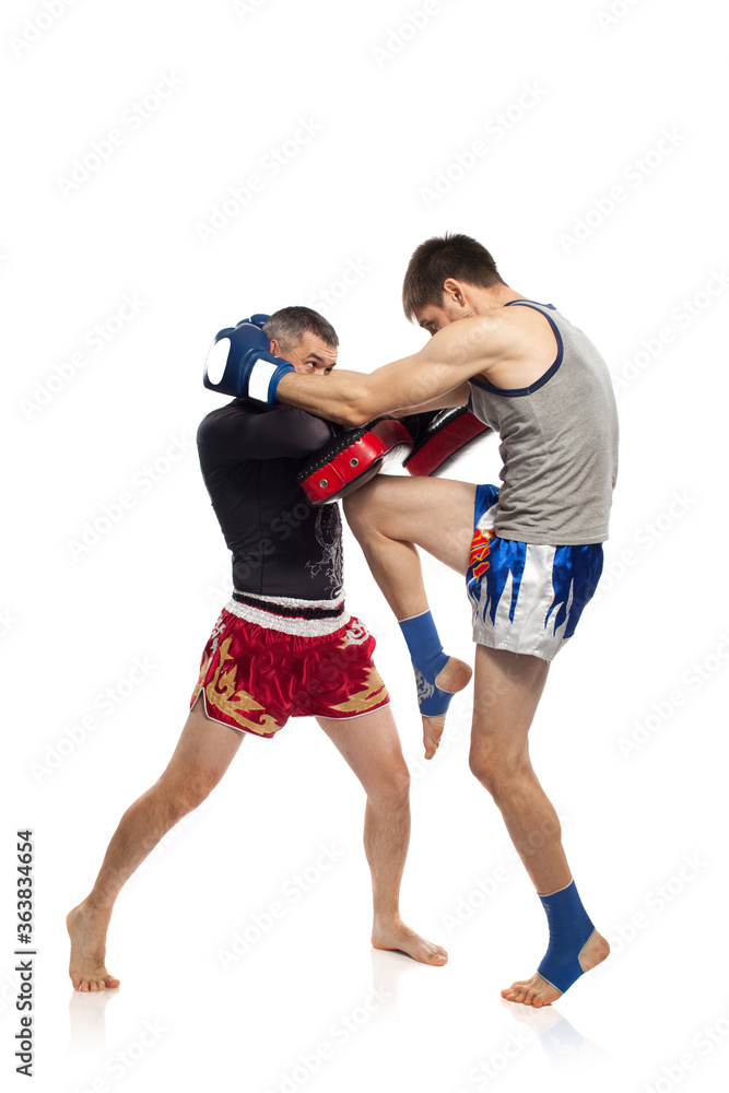 Two caucasian men exercising thai boxing in studio on white background Two caucasian men exercising thai boxing in studio on white background