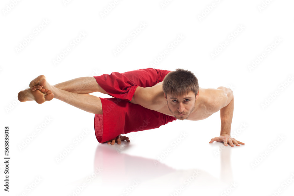 Caucasian adult man doing yoga exercises in studio at white background Caucasian adult man doing yoga exercises in studio at white background