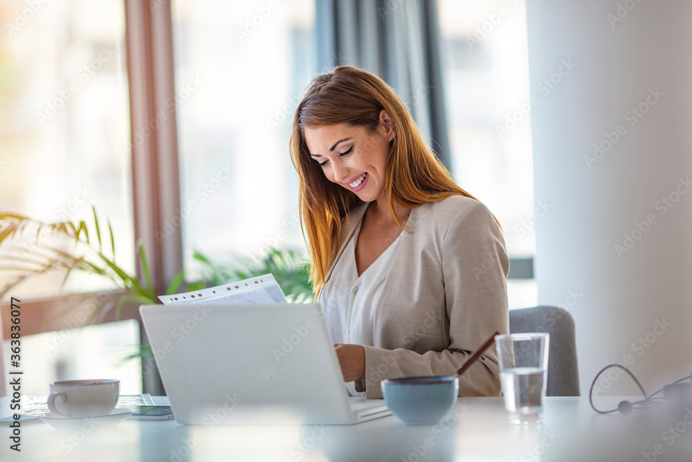 Successful young woman in modern office working on laptop. Female businesswoman readind financial report analyzing statistics pointing at pie chart working at her desk Successful young woman in modern office working on laptop. Female businesswoman readind financial report analyzing statistics pointing at pie chart working at her desk