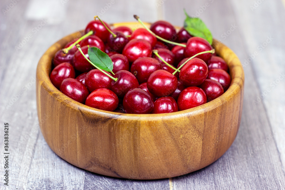 Fresh juicy red sweet cherry berries in the wooden bowl on light background in summer. Fresh juicy red sweet cherry berries in the wooden bowl on light background in summer.