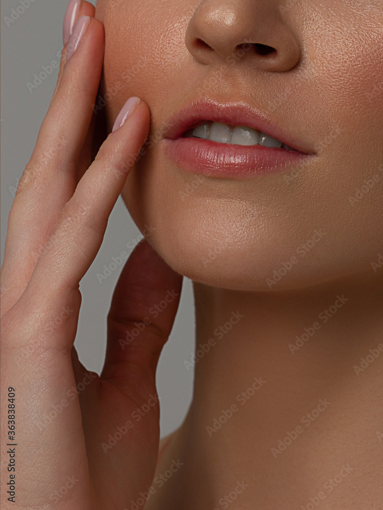 Fototapeta premium Sexual full lips. Natural gloss of lips and woman's skin. The mouth is closed. Increase in lips, cosmetology. Natural lips. Great summer mood with open eyes. fashion jewelry. Pink lip gloss