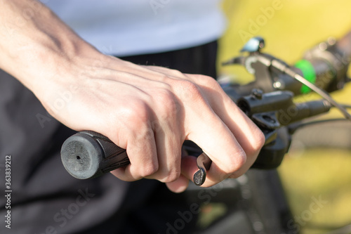 Close up of a mans hand holding onto the bicycle steering wheel, holding the brake pressed.
