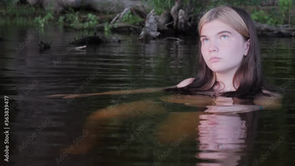 girl is reflected in the dark water at sunset girl is reflected in the dark water at sunset