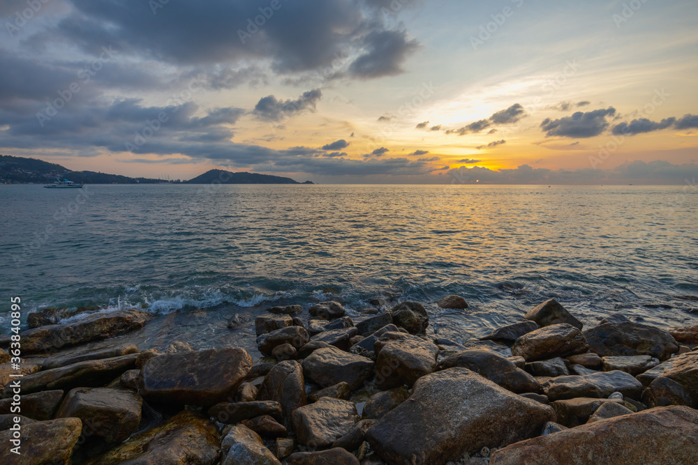 Landscape of sunset beach with stones on the shore