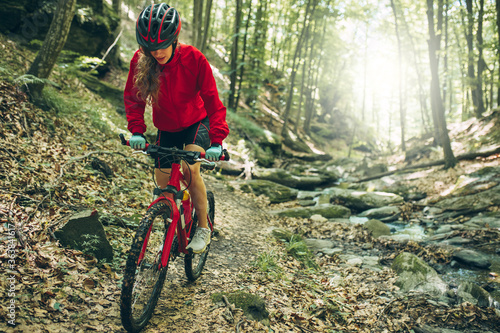 Mountain Bike cyclist woman riding bike in forest. Outdoor cyclist woman enjoying at nature. photo