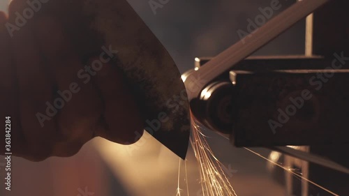 Man sharpening knife with sparks. Work on a sharpening machine.