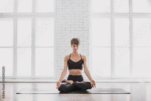 Young beautiful woman practicing yoga in studio. Fit girl doing exercise at home. Workout, recreation, self care, yoga training, fitness, breathing, meditation, relaxation, healthy lifestyle concept