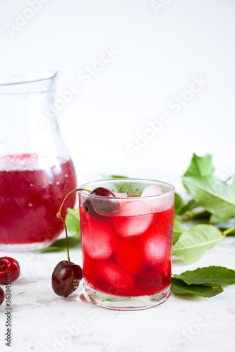 Wallpaper Mural Cold summer drink with red ice in a glass glass on a light background. Cherry berries and green leaves in the background. Torontodigital.ca