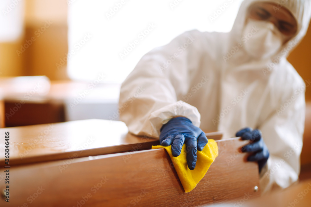 Cleaning and disinfection school class to prevent COVID-19. Man in protective hazmat suit washes school desk  to preventing the spread of coronavirus, pandemic in quarantine city.