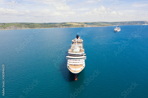 Cruise ships at anchor off the coast of England during the Coronavirus Covid19 sailing pause in operations. Aerial view with space for text.