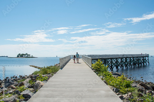 A view down the pier boardwalk on a beautiful summer day by the Long Island Sound at Calf Pasture Beach in Norwalk, Connecticut USA photo