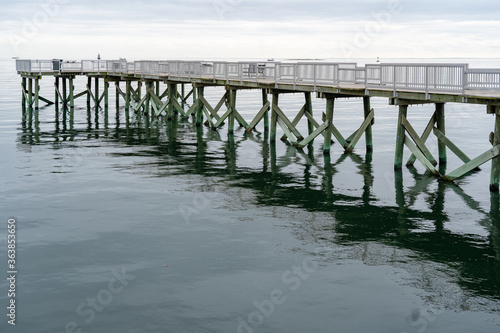 A view of the long pier and the Long Island Sound at Calf Pasture Beach in Norwalk, Connecticut USA on a cold and grey December day. The flat light lends a dreamy feel to the scene.