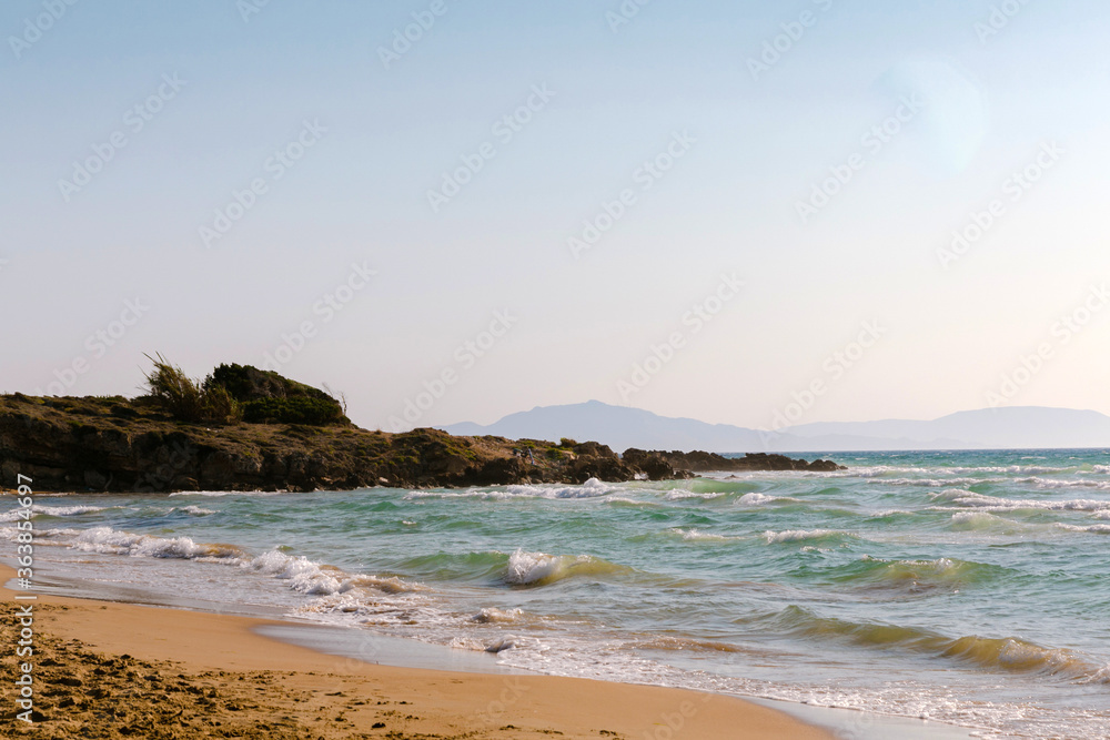 Sandy beach of Peloponesse island, Greece. Windy weather in the summer. Waves at sea. Very gentle entrance to the sea. Warm pleasant caressing sea. Holidays in Greece for the whole family.