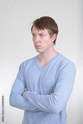 Portrait of young handsome man thinking with arms crossed © Ranta Images