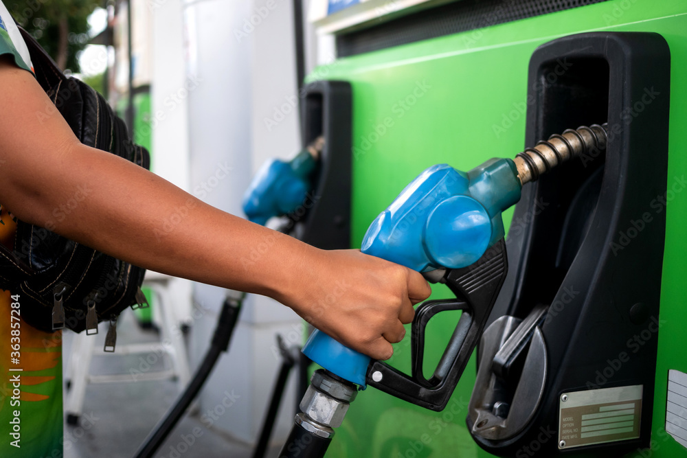 hand with Fuel oil gasoline dispenser at petrol filling station.Holding fuel nozzle to refuel gasoline for car. hand with Fuel oil gasoline dispenser at petrol filling station.Holding fuel nozzle to refuel gasoline for car.