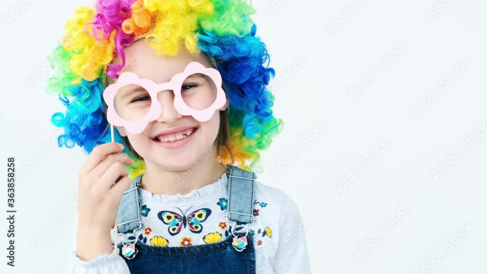 Laughing girl in clown wig posing with paper photo glasses Laughing girl in clown wig posing with paper photo glasses