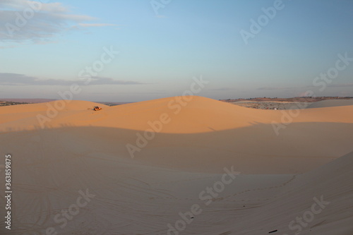 mound in the desert in the morning has a sky background and there is a car running in the desert. There is sunshine in the morning.