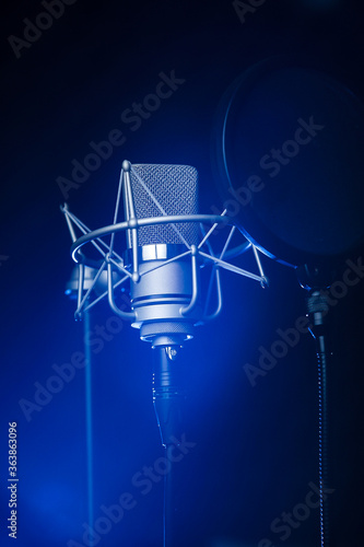 Neumann TLM 102 studio recording microphone in the dark with a spotlight on it photo