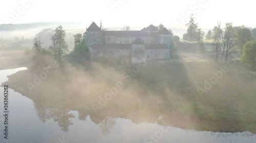 Aerial view of Svirzh castle near Lviv, Ukraine at dawn. Lake, morning fog and surrounding landscape at sunrise. photo